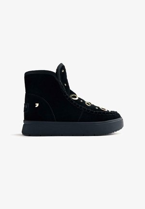 Sneaker alta in suede nero con suola spessa nera, occhielli dorati e dettagli intrecciati sul davanti. Logo sottile sul lato.