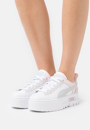 White platform sneakers with pink and gray accents, smooth leather, rounded toe, and padded collar. Features sturdy rubber outsole and laces.