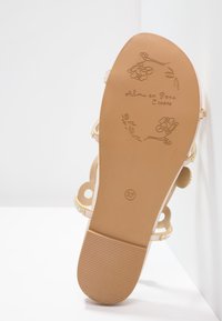 Sole sandálů s květinovým embosovaným designem, značka "Alma en Pena España", velikost 37 a viditelné béžové pásky s detailem z kamínků.