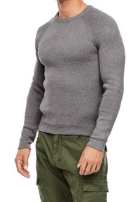 Pull en maille côtelée gris avec un col rond et des manches longues, design ajusté, associé à un pantalon cargo vert olive.