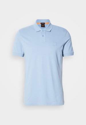 Helesinine puuvillane polo särk, millel on struktureeritud krae, kahe nupuga nööpaugu ja väike logo silt rinnal.