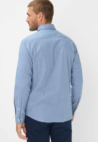 Camicia a maniche lunghe con colletto e polsini, a quadri blu e bianchi. Realizzata in tessuto leggero, presenta una vestibilità morbida.