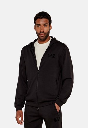 Sudadera con cremallera de color negro, hecha de una tela suave, cuenta con capucha ajustable, bolsillos laterales y un logotipo bordado de EA7 en el pecho.