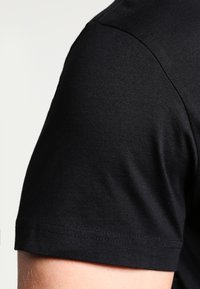 Black cotton t-shirt featuring a crew neck and short sleeves. Smooth texture with a fitted silhouette and clean stitching details.