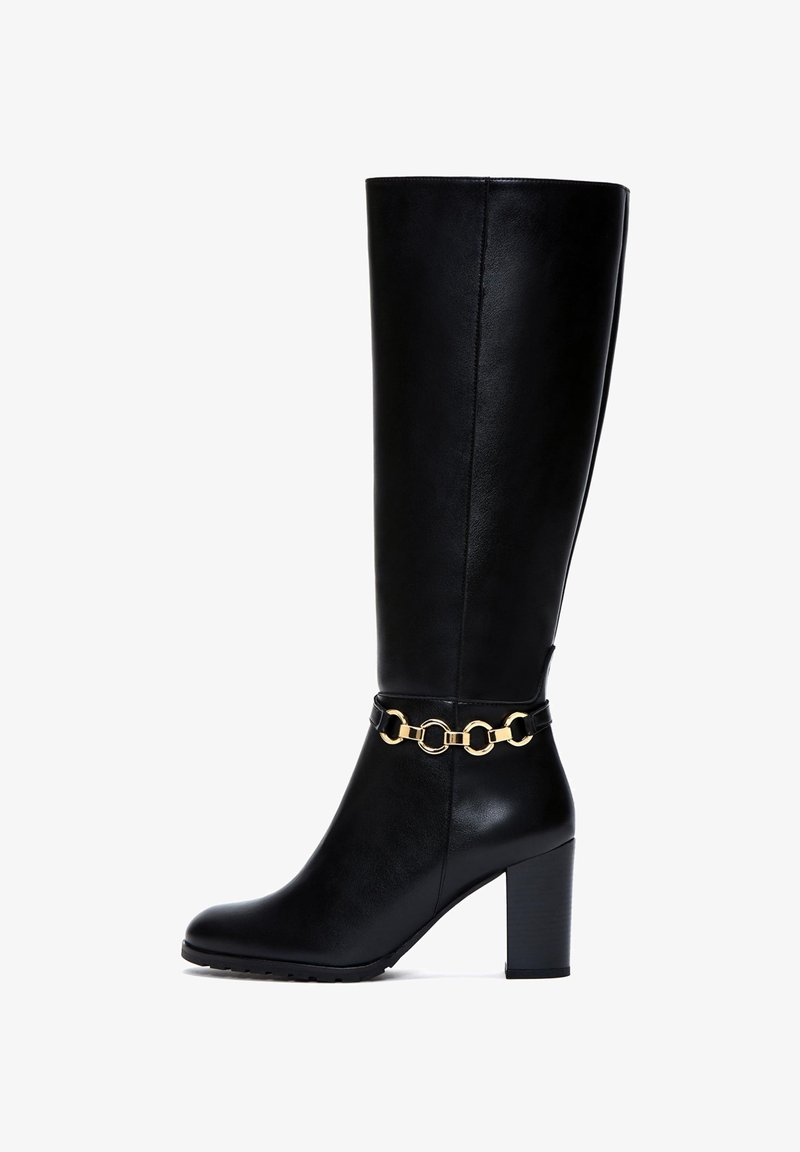 Botte noire mi-mollet en simili cuir avec une texture lisse, dotée d'un détail en chaîne dorée chunky autour de la tige et d'un talon épais.