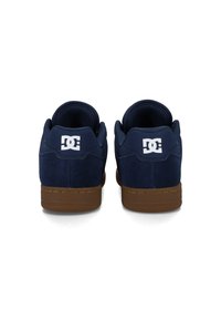 Námořnické modré semišové tenisky s hnědou gumovou podrážkou, vybavené polstrovaným límcem a bílým logem na patě.