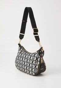 Borsa hobo con tessuto a fantasia bianco e nero, hardware dorato e tracolla nera testurizzata. Presenta una chiusura a zip e dettagli con logo.