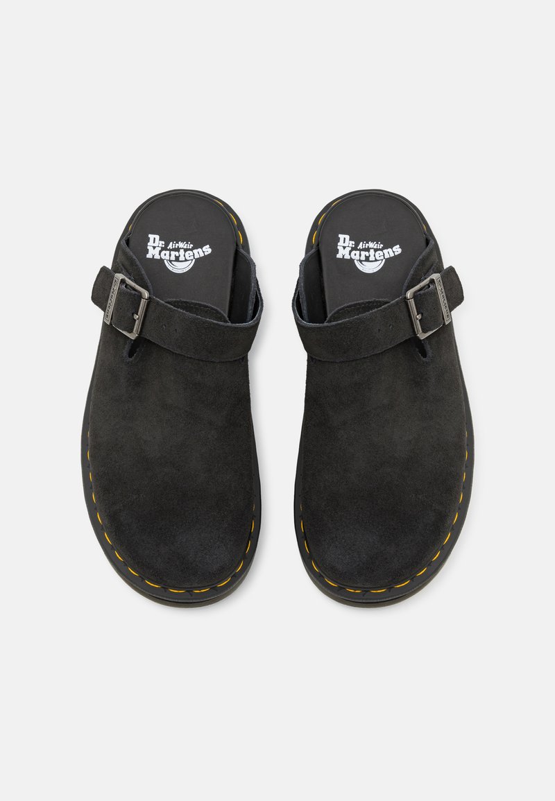 Schwarze Wildleder-Clogs mit einem verstellbaren Schnallenverschluss, ausgestattet mit einer gepolsterten Innensohle und charakteristischen gelben Nähten entlang der schwarzen Gummisohle.