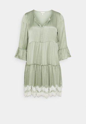 Robe en satin vert clair avec manches 3/4, col en V, taille froncée, jupe à volants et bordure en dentelle blanche à l'ourlet.