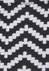 Schwarz-weißer Zickzackmuster mit geschwungenen, wolkenartigen Kanten auf einem strukturierten Hintergrund aus Stoff.