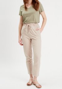 T-shirt vert clair à col en V associé à un pantalon beige à taille élastique avec poches. Tissu doux et coupe décontractée avec une conception de jambe fuselée.