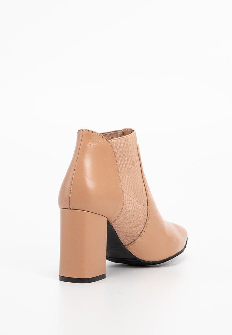 Beige Leder Stiefelette mit Blockabsatz, elastischer Seitenpartie und schwarzem Sohle, fotografiert vor einem weißen Hintergrund.