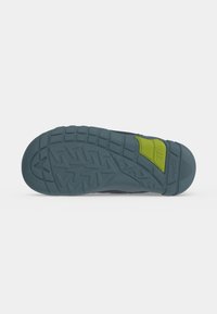 Semelle de chaussure bleu foncé avec un motif de bande de roulement texturé et une section verte près du talon affichant le numéro 27 sur un fond clair.