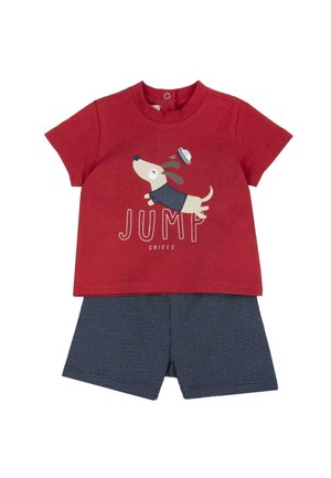 Chemise rouge à manches courtes avec une illustration d'un chien sautant portant un chapeau de marin et un short bleu marine à petits pois blancs.