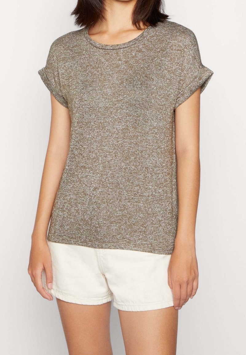Krátký rukáv, kulatý výstřih, top z texturovaného hnědého pleteného materiálu, v kombinaci s bílými šortkami; má ohrnuté manžety rukávů a volný střih.