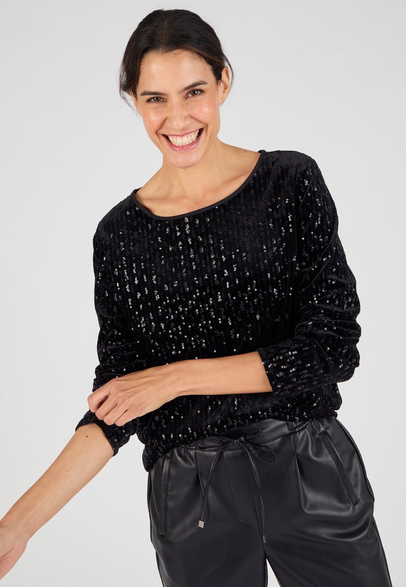 Suéter negro con lentejuelas, de corte suelto, escote redondo, tejido texturizado, mangas largas y dobladillo fruncido, combinado con pantalones de cuero negros.