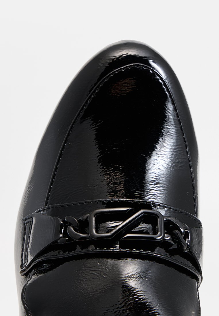 Schwarze Lackleder-Slipper mit spitzer Zehenform, ausgestattet mit einem breiten Riemen und geometrischem Metallakzent darüber. Glatte Textur und hochglänzende Oberfläche.