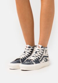 Höga sneakers i denim i en blå och vit färgskala. Har vita snören, en vadderad krage och en förstärkt tåhätta.