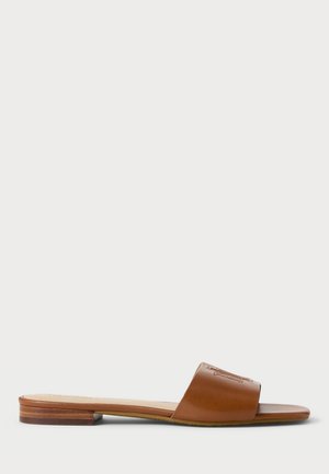 Brun læder slide-sandal med flad sål og bred rem, der er præget med en syet monogramlogo på en hvid baggrund.