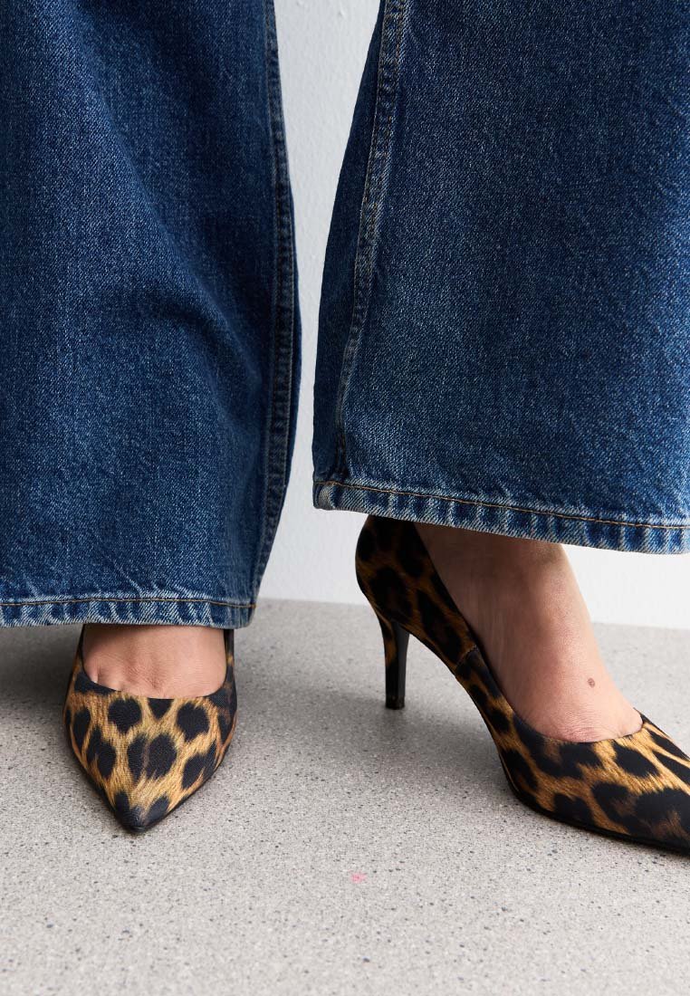 Leopardmönstrade högklackade skor med spetsiga tår, tillverkade av satin. Kombinerade med vida denimjeans med rå kant. Neutral strukturerad golv.