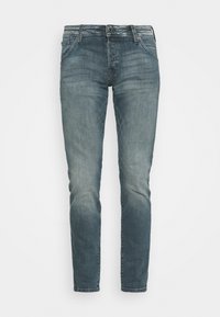 Slim fit avblekta blå jeans med fickor fram och bak samt knappstängning, visade mot en vit bakgrund.