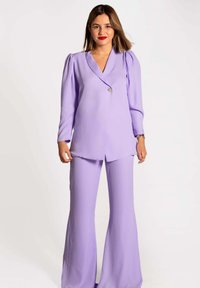 Conjunto de dos piezas en color lila que incluye un blazer de manga larga con hombros abullonados y pantalones acampanados, fabricado con una tela suave y con un diseño de minimalismo.