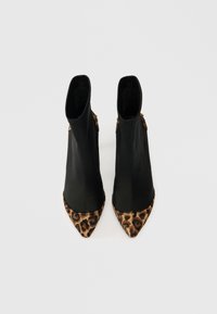Bottes noires à la cheville avec un bout pointu et des accents en imprimé léopard. Fabriquées en cuir lisse avec un design épuré et des détails subtils sur les côtés.