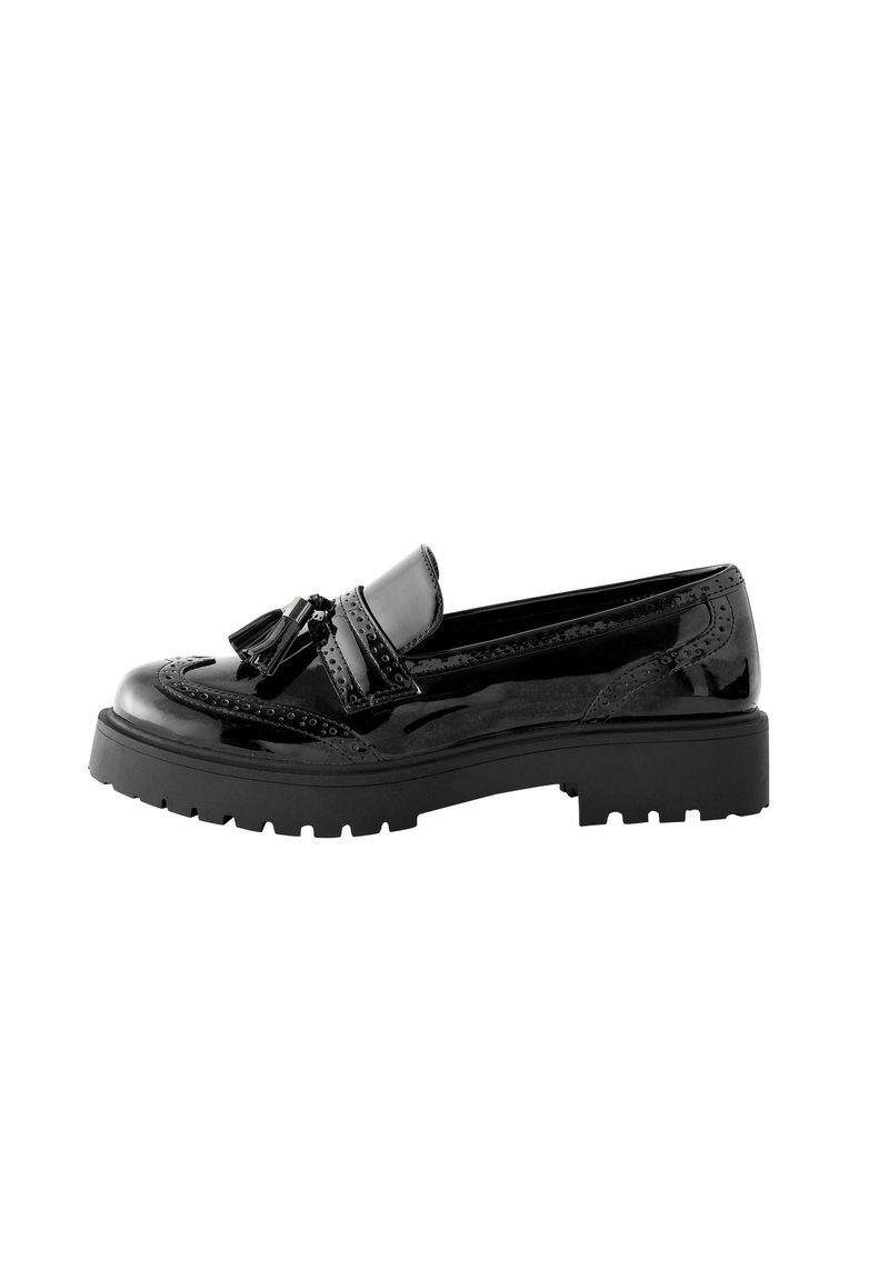Mocasin de charol negro con detalles de borlas, acentos de brogue, punta redondeada y suela de goma gruesa. Textura suave y acabado pulido.