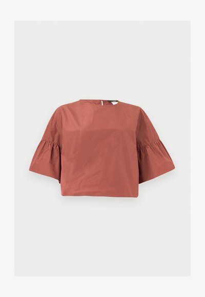 Blouse courte de couleur rouille avec des manches larges à volants arrivant aux coudes et une petite fermeture par bouton dans le dos.