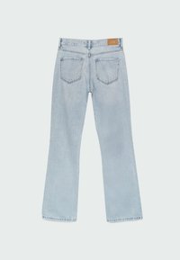 Jeans de mezclilla azul claro de corte acampanado con una cintura de altura media, dos bolsillos traseros, costuras visibles y una etiqueta cosida en la cinturilla.