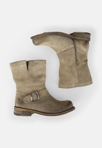 Stivaletti beige in suede con punta arrotondata, lampo laterale e dettaglio a fibbia decorativa. Tacco basso a blocco e suola in gomma testurizzata.