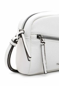 Valge tekstureeritud nahast crossbody kott kahe lukuga ja ühtse reguleeritava rihmaga.