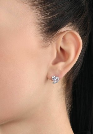 Orecchini a forma di cuore in argento, con un grande gemma trasparente centrale e piccole cristalli circostanti, caratterizzati da una finitura liscia e lucida.