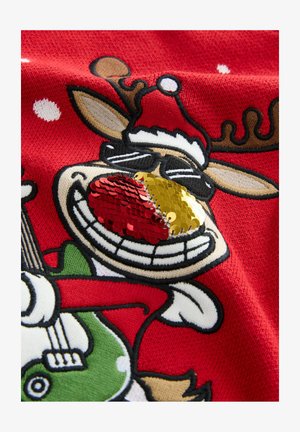 Raudonas megztas audinys su animaciniu elniu, dėvinčiu Kalėdų senelio skrybėlę. Elnias turi blizgančius raudonus ir auksinius akcentus ant nosies ir laiko žalią gitarą.