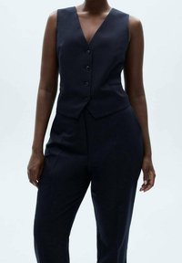 Námořnická vesta s výstřihem do V, pěti knoflíky a upraveným střih a, spárovaná s odpovídajícími kalhotami s vysokým pasem pro soudržný vzhled.