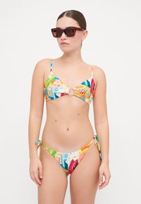 Fargerik to-delt bikini med blomsterdesign, en sirkulær detalj ved bysten, og justerbare sidestrammere på bunnene.