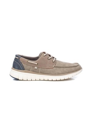 Zapato de lona gris con acentos beige y tacón azul marino, que presenta cordones, detalles de costura y una suela de goma blanca flexible.
