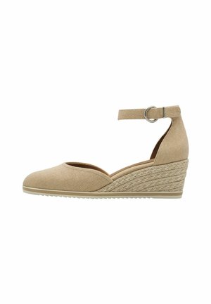 Zapato cuña de lona beige con tira en el tobillo, punta redonda y detalles de yute trenzado en el tacón. Suela de goma plana para mayor agarre.