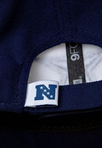 Close-up of navy blue cap's interior showing size tag "9F" and white fabric label with blue "N" and four white stars.