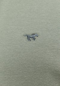 Mały, ciemnoszary, haftowany koń biegający na jasnoszarej dzianinie.