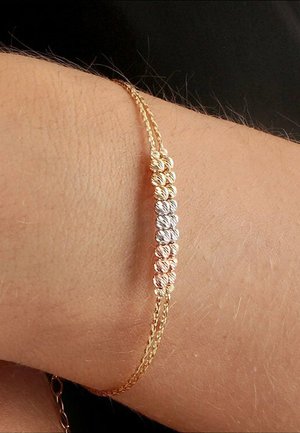 Gold- und Silberschmuckarmband mit gedrehten und glatten Gliedern, das ein Muster aus abwechselnden goldenen und silbernen Segmenten an einem Handgelenk aufweist.