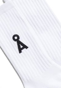 Calzini bianchi con texture a costine, con un logo nero della lettera 'A' lavorato sul lato.