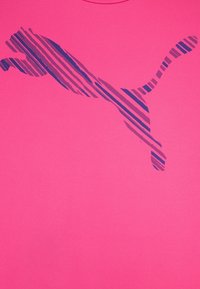 Camiseta rosa con un diseño del logo de Puma a rayas azules. La tela parece suave, con un cuello redondo y un corte regular.