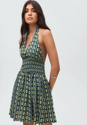 Abito senza maniche con scollatura all'americana, corpino aderente, vita arricciata e gonna svasata. Caratterizzato da un tessuto verde scuro con un motivo floreale giallo.