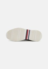 Talpa de sneaker din cauciuc, cu o suprafață texturată și caneluri verticale. Paleta de culori include alb, cu dungi roșii și albastre.