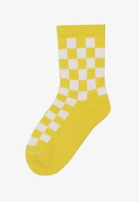 Calzino di cotone giallo con un motivo a scacchi bianco. Polsino a costine nella parte superiore e texture liscia su tutta la superficie.