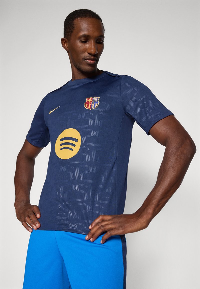 Camiseta de fútbol de manga corta azul marino con diseño texturizado, logo dorado de Barcelona y gran logo amarillo de Spotify en el centro.