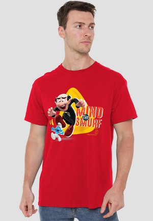 Rotes Baumwoll-T-Shirt mit einem bunten Cartoon-Grafik eines Charakters und einer blauen Figur, mit dem auffällig platzierten Text "MIND THE SMURF".