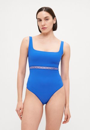 Costume da bagno intero blu con scollatura quadrata, spalline larghe e un accento in rete trasparente in vita. Tessuto morbido ed elastico.