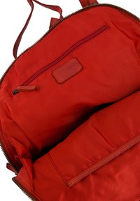 Czerwony płócienny worek od środka z gładką teksturą, kieszonka na zamek błyskawiczny oraz skórzana metka z nazwą marki. Miękka podszewka, pojemne przegrody.